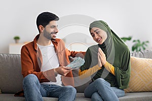 Middle Eastern Husband Giving Money To Wife Sitting At Home