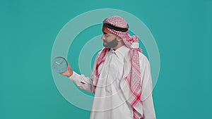 Middle eastern man checks wall clock