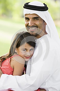 A Middle Eastern man and his daughter in a park