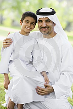 A Middle Eastern man and his son sitting in a park