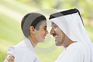 A Middle Eastern man and his son sitting in a park