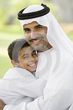 A Middle Eastern man and his son sitting in a park