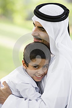 A Middle Eastern man and his son sitting in a park