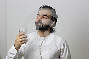 Middle Eastern Man Holding A Glass Of Water With Closed Eyes Enjoying The Taste