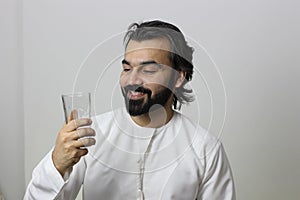 Middle Eastern Man Holding A Glass Of Water And Looking Into The Glass Very Happy