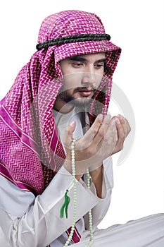 Middle eastern man holds beads and praying