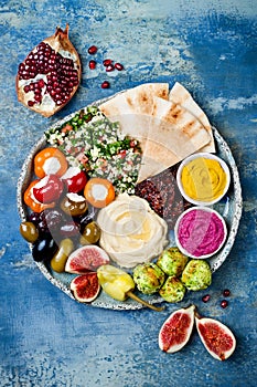 Middle Eastern meze platter with green falafel, pita, sun dried tomatoes, pumpkin, beet hummus, olives, stuffed peppers, tabbouleh