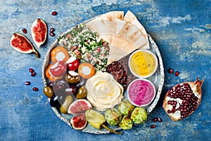 Middle Eastern meze platter with green falafel, pita, sun dried tomatoes, pumpkin, beet hummus, olives, stuffed peppers, tabbouleh photo