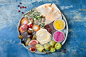 Middle Eastern meze platter with green falafel, pita, sun dried tomatoes, pumpkin, beet hummus, olives, stuffed peppers, tabbouleh