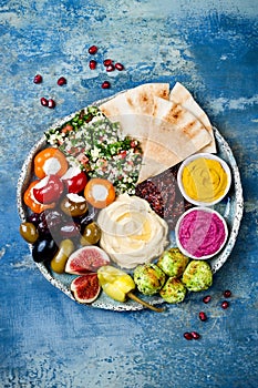 Middle Eastern meze platter with green falafel, pita, sun dried tomatoes, pumpkin, beet hummus, olives, stuffed peppers, tabbouleh