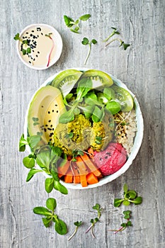 Middle eastern style Buddha bowl with green falafel, quinoa, butternut squash, tomatoes, avocado, beetroot hummus and tahini sauce