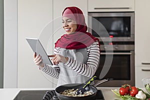 Middle eastern woman in hijab checking recipe on Internet