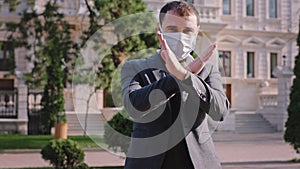 In the middle of empty street man with a protective mask suggesting to the people to wearing mask to stop walking on the
