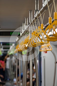 Middle focus of Plastic Grab Handles or straps lined up and hung on a metal bar.