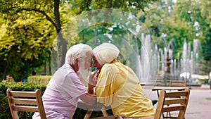 In the middle of the park at cafe amazing old couple speeding romantic time together hugging hands and looking to each