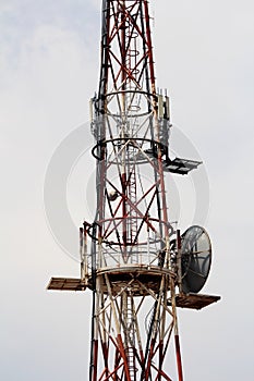 Middle part of strong tall cell phone red and white antenna tower with multiple antennas and transmitters
