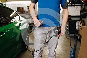 Middle selection of male mechanic holds a tire inflator at garage