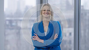 Middle shot of confident gorgeous Caucasian woman crossing hands looking at camera smiling. Portrait of successful slim