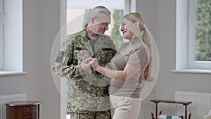 Middle shot of loving happy woman and military man talking and hugging at home. Portrait of positive Caucasian middle