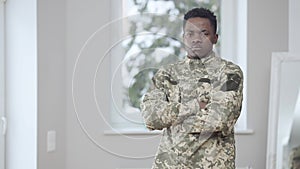 Middle shot of patriotic brave African American man in military uniform crossing hands looking at camera with serious