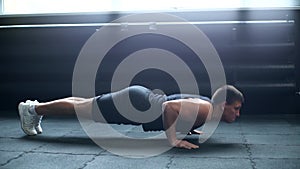 Middle shot portrait of muscular strong man doing push-ups exercise on the floor