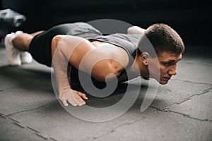 Middle shot portrait of muscular strong man doing push-ups exercise on the floor