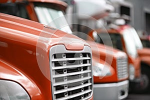 Middle sized rigs semi trucks standing in row in warehouse dock