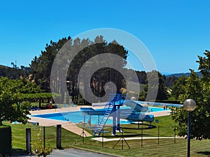 In the middle, some trees and lots of green grass, the pool and slides