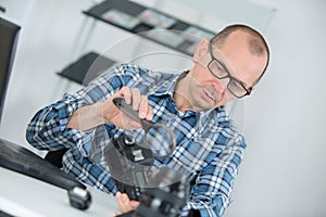 Middlea ged man examining dslr camera with mgnifying glass