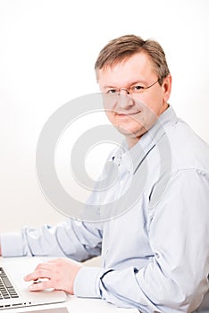 Middleaged man in glasses working on laptop