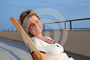 Middleaged woman in lounge on veranda over sea