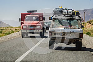 Midelt, Morocco - April 11, 2015. Fully loaded off road car on road trip passing by red vintage truck
