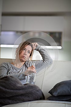 Midlle aged woman at home with a bottle of strong alcohol