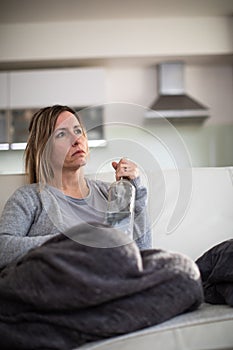 Midlle aged woman at home with a bottle of strong alcohol photo