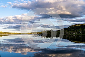 Midnight sun in northern Sweden with calm dark sky and reflections in mountain lake.