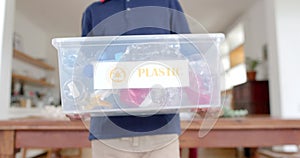 Midsection of african american boy holding recycling box in kitchen, slow motion