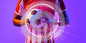 Midsection of african american male soccer player holding ball by illuminated circle and plants