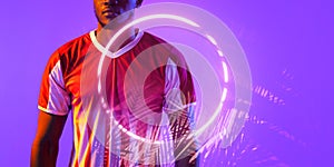 Midsection of african american male soccer player standing by illuminated plant and circle