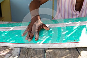 Midsection of african american man preparing surfboard behind counter of surf hire beach shack