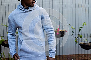 Midsection of african american man wearing grey hooded sweatshirt against white fence, copy space