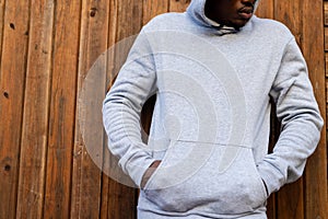 Midsection of african american man wearing grey hooded sweatshirt against wooden fence, copy space