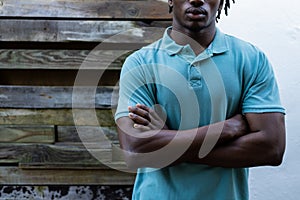 Midsection of african american man wearing pale blue polo shirt against wooden fence, copy space