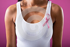 Midsection of african american mid adult woman with pink breast cancer awareness ribbon on tank top