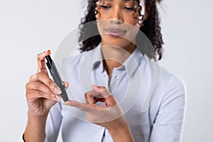 Midsection of african american mid adult woman using lancet for sugar test against white background