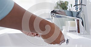 Midsection of african american woman rinsing hands thoroughly in bathroom sink, slow motion