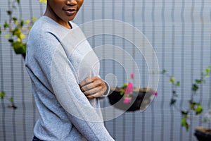 Midsection of african american woman wearing grey sweatshirt against white fence, copy space