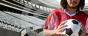 Midsection of african american young male soccer player with ball at stadium, copy space