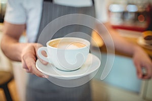Midsection of barista serving coffee at shop
