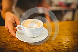 Midsection of barista serving heart shape frothy coffee at cafe