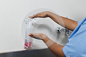 Midsection of biracial female doctor wearing scrubs washing hands in operating theatre